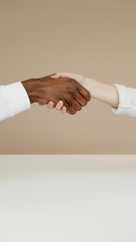 Close-up of a diverse handshake symbolizing unity and cooperation on a neutral background.